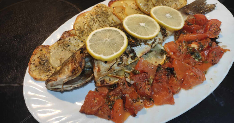 Sardinian baked seabass served with roasted vegetables and fresh herbs, highlighting the simplicity and flavor of Mediterranean cuisine.