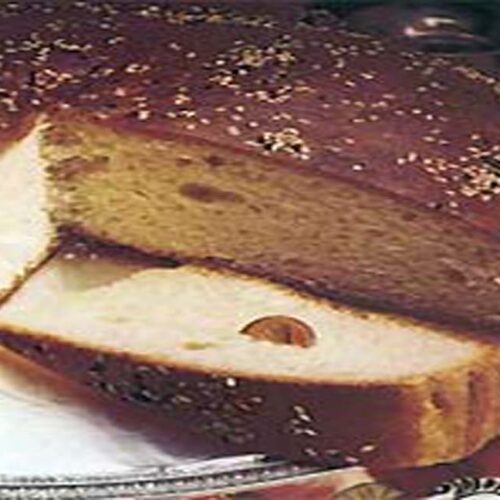 A beautifully Greek Vasilopit, almond slices, with a gold coin symbolizing the New Year tradition, set in a festive holiday ambiance.