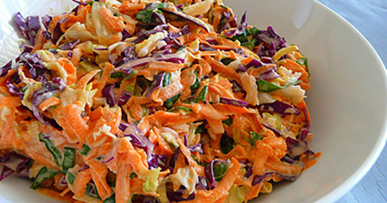 A vibrant bowl of Politiki Salata with shredded white and red cabbage, grated carrots, celery, and parsley, dressed with a tangy lemon vinaigrette.