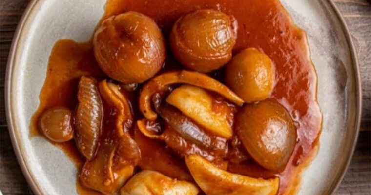 A bowl of traditional Greek cuttlefish stifado, featuring tender cuttlefish pieces in a rich tomato sauce with pearl onions, served with crusty bread.