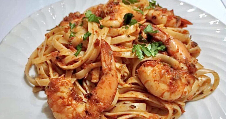 Plate of shrimp fra diavolo served over pasta with spicy tomato sauce, garnished with parsley and red pepper flakes
