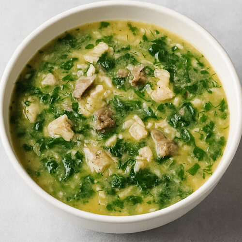 Close-up of Chicken Magiritsa Greek Easter soup with spinach, rice, and avgolemono, garnished with fresh dill.